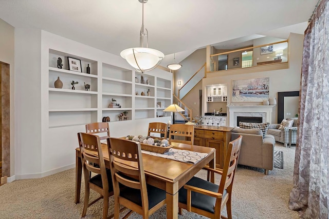 carpeted dining room with a premium fireplace and built in features