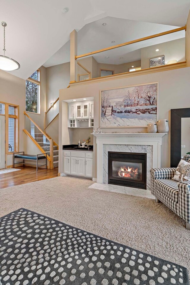 living room with hardwood / wood-style floors, sink, high vaulted ceiling, and a premium fireplace