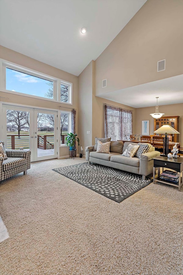 carpeted living room featuring french doors and high vaulted ceiling