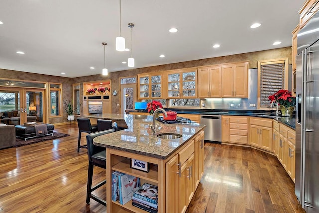 kitchen featuring sink, hardwood / wood-style flooring, an island with sink, decorative light fixtures, and stainless steel appliances