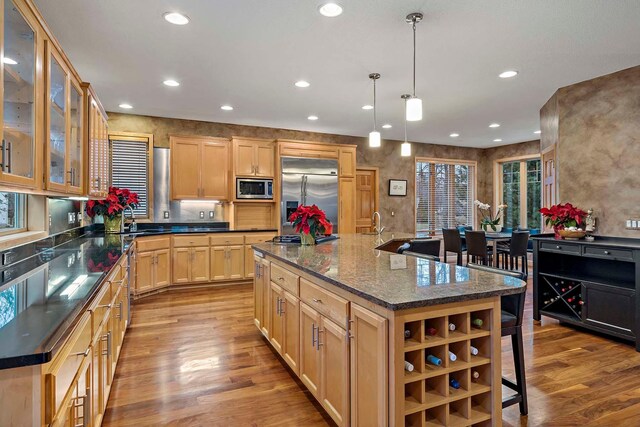 kitchen featuring built in appliances, decorative light fixtures, a kitchen island, and light hardwood / wood-style flooring