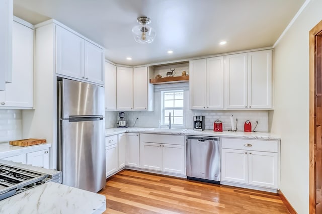 kitchen with backsplash, stainless steel appliances, sink, light hardwood / wood-style flooring, and white cabinetry