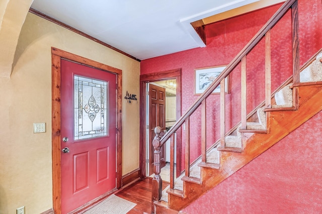 entryway with crown molding and dark wood-type flooring