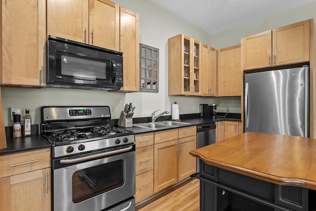 kitchen with light brown cabinetry, sink, stainless steel appliances, and light hardwood / wood-style flooring