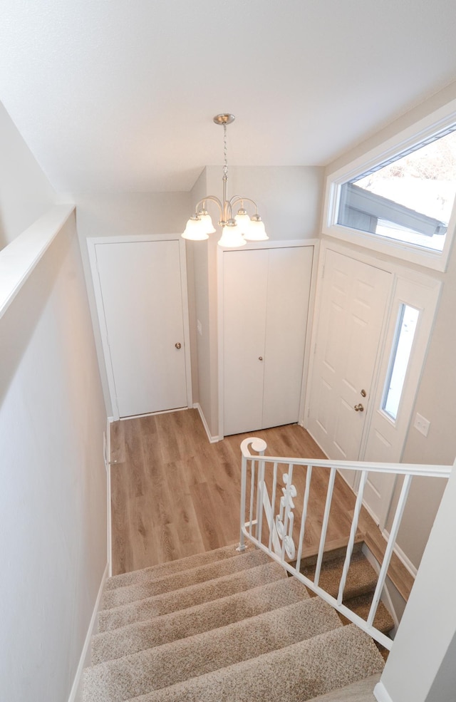 stairway featuring hardwood / wood-style flooring and a notable chandelier