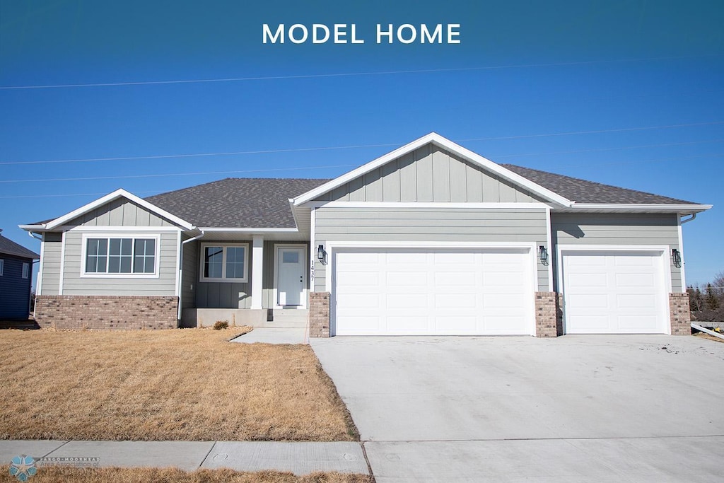 1437 66th Ave S, Fargo, ND 58104 - view of front of home with brick siding, driveway, an attached garage, and board and batten siding