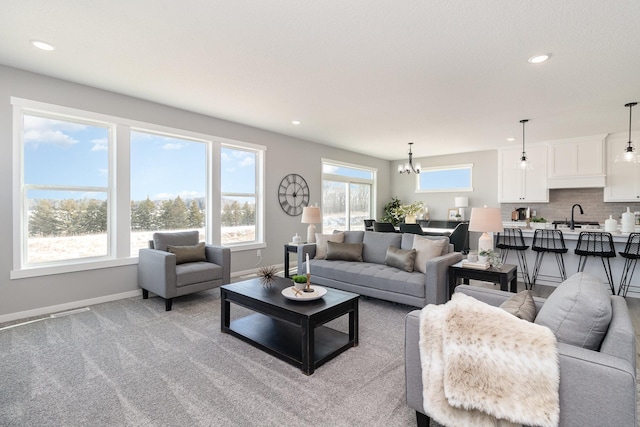 living room featuring a chandelier, sink, light carpet, and a wealth of natural light