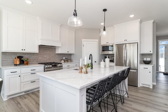 kitchen featuring appliances with stainless steel finishes, sink, a center island with sink, and white cabinets