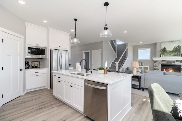 kitchen with a kitchen island with sink, sink, white cabinets, and appliances with stainless steel finishes