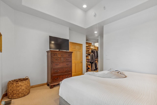 bedroom featuring a walk in closet, a closet, a towering ceiling, and light colored carpet