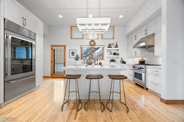 kitchen featuring refrigerator, white cabinetry, designer stove, and decorative light fixtures