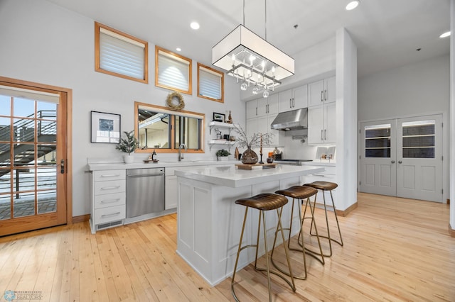 kitchen featuring a kitchen breakfast bar, pendant lighting, dishwasher, a center island, and white cabinetry