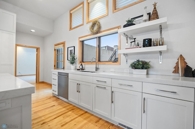 bar with dishwasher, light wood-type flooring, white cabinets, and sink