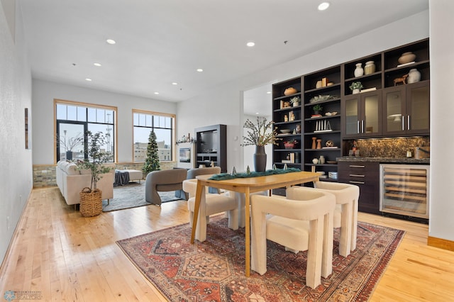 dining room with bar, wine cooler, and light hardwood / wood-style flooring