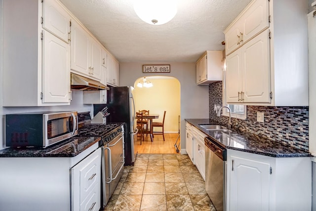 kitchen featuring white cabinets, sink, dark stone countertops, a textured ceiling, and stainless steel appliances