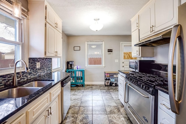 kitchen featuring white cabinets, sink, decorative backsplash, dark stone countertops, and stainless steel appliances