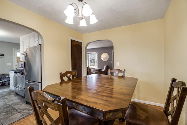 dining space with hardwood / wood-style flooring, a notable chandelier, and a textured ceiling