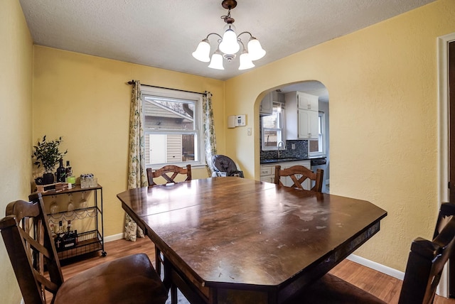 dining area featuring hardwood / wood-style floors, a chandelier, a textured ceiling, and sink