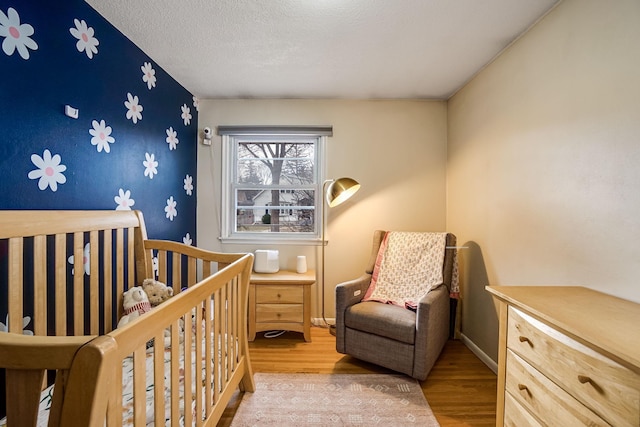 bedroom featuring a textured ceiling, hardwood / wood-style flooring, and a nursery area