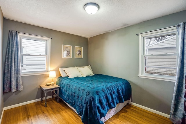 bedroom featuring wood-type flooring, a textured ceiling, and multiple windows