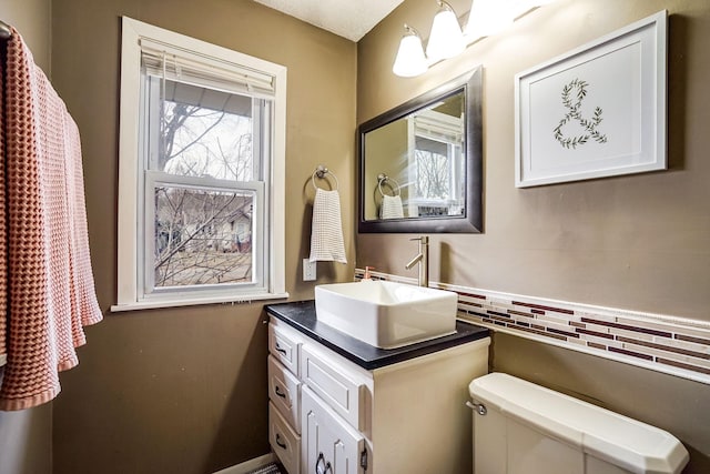 bathroom featuring vanity, toilet, a textured ceiling, and tasteful backsplash