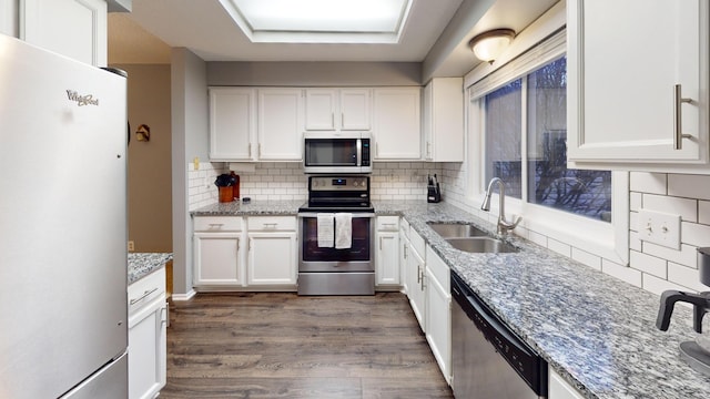 kitchen with white cabinets, sink, dark hardwood / wood-style floors, appliances with stainless steel finishes, and tasteful backsplash