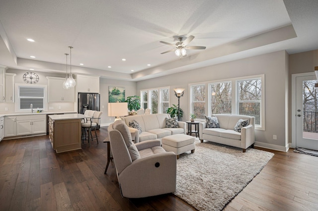 living room with a raised ceiling, sink, ceiling fan, dark hardwood / wood-style floors, and a textured ceiling