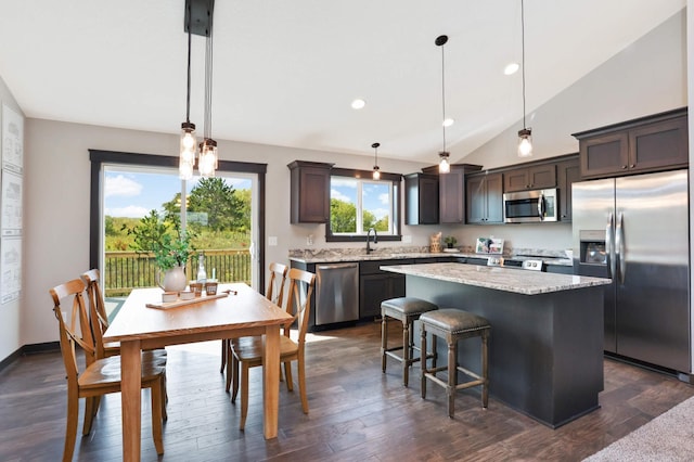 kitchen featuring stainless steel appliances, hanging light fixtures, a center island, and dark brown cabinetry