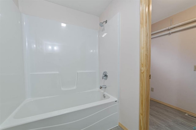 bathroom with hardwood / wood-style flooring and bathing tub / shower combination