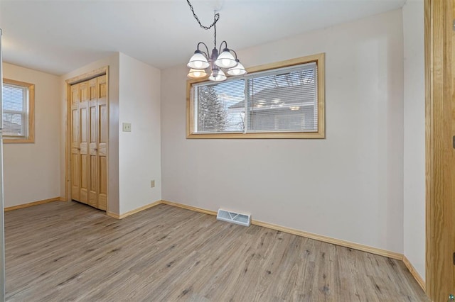 unfurnished dining area featuring light wood-type flooring and an inviting chandelier