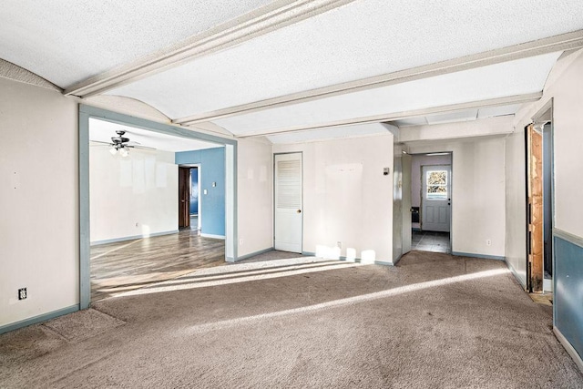 empty room featuring ceiling fan, beamed ceiling, carpet floors, and a textured ceiling