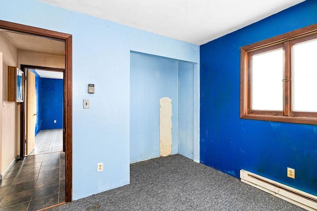 unfurnished bedroom with dark colored carpet, a closet, and a baseboard radiator