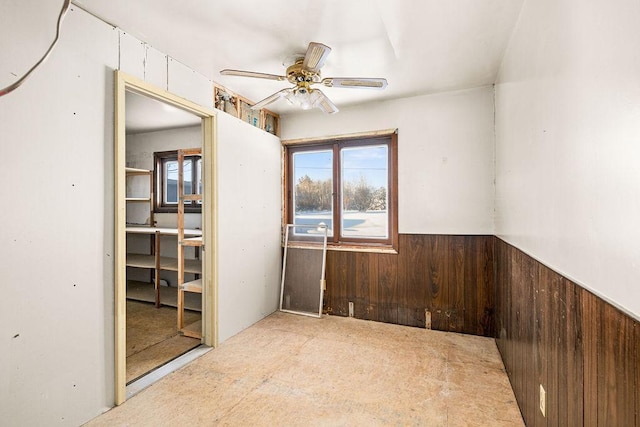 unfurnished room featuring ceiling fan and wood walls