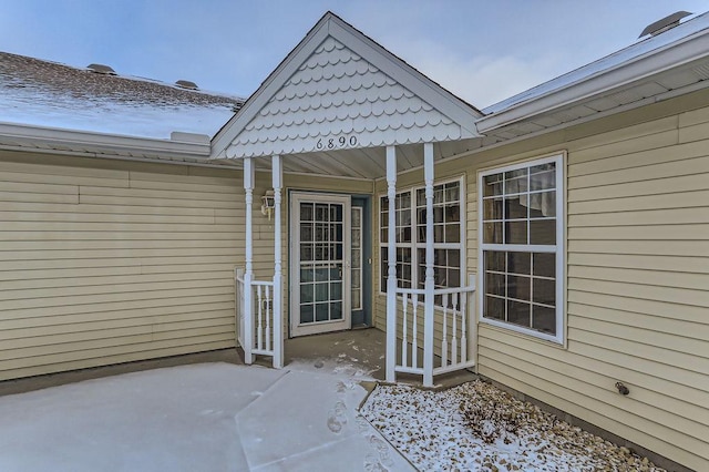 snow covered property entrance featuring a patio area