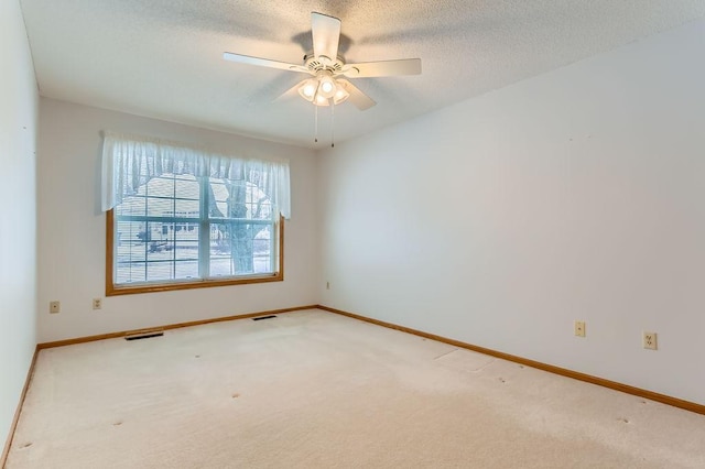 carpeted spare room featuring ceiling fan and a textured ceiling