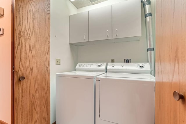 clothes washing area with cabinets and washing machine and dryer