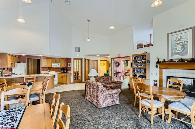 carpeted dining space featuring a fireplace and high vaulted ceiling