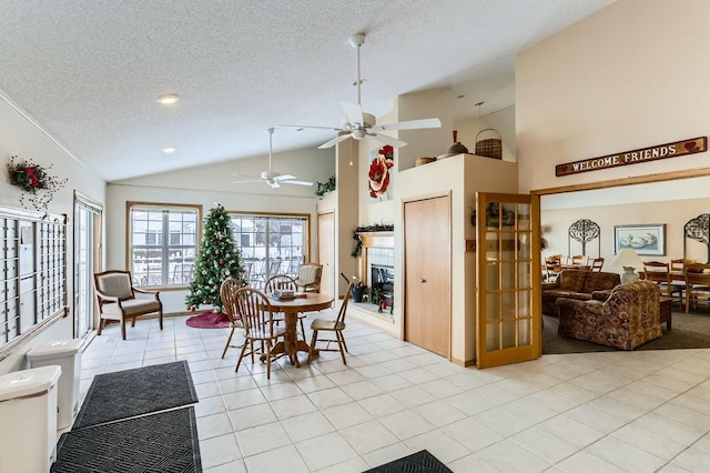 tiled dining room featuring ceiling fan, a textured ceiling, and high vaulted ceiling