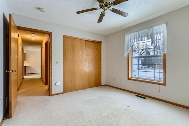 unfurnished bedroom with light colored carpet, a closet, visible vents, and a textured ceiling