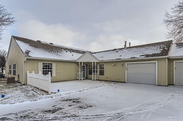 ranch-style house featuring an attached garage, fence, and central AC unit