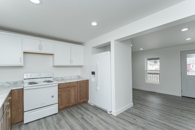 kitchen featuring light stone countertops, white appliances, light hardwood / wood-style floors, and white cabinetry