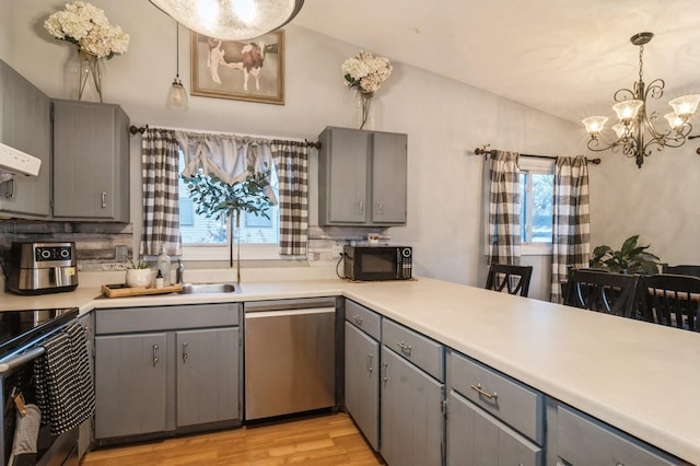 kitchen with vaulted ceiling, stainless steel appliances, gray cabinets, and hanging light fixtures