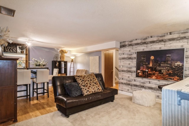 living room with wooden walls, wood-type flooring, and a textured ceiling