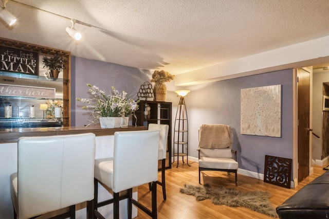 dining area featuring wood-type flooring and a textured ceiling