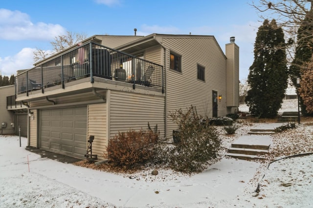 view of snow covered exterior with a garage and a balcony