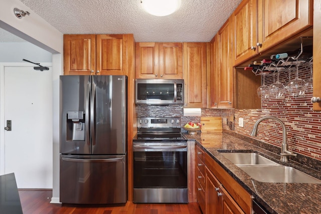 kitchen with sink, stainless steel appliances, dark stone counters, and dark wood-type flooring