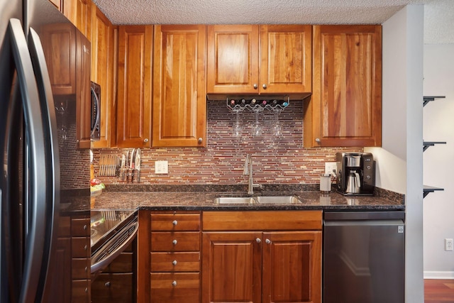 kitchen featuring dark stone counters, sink, hardwood / wood-style flooring, appliances with stainless steel finishes, and tasteful backsplash