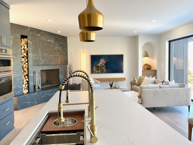 3702 Planting Grn, Stillwater, MN 55082 - kitchen with a fireplace, recessed lighting, stainless steel double oven, a textured ceiling, and stone countertops