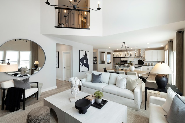 living room featuring a notable chandelier, a high ceiling, and light hardwood / wood-style flooring