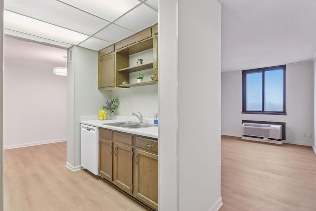 kitchen with sink, a drop ceiling, a wall mounted AC, white dishwasher, and light hardwood / wood-style floors